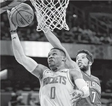  ?? John Raoux / Associated Press ?? Russell Westbrook, left, goes to the basket past Orlando’s Michael Carter-Williams during the first half of Friday’s game at Orlando, Fla. Westbrook had 23 points, seven rebounds and six assists in the Rockets’ win.