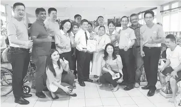  ??  ?? James (standing front row, fourth left) presenting a pennant to Sister Regina Lachau of Cheshire Home, witnessed by Namlifa members during the visit.