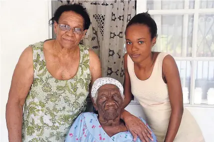  ?? OKOYE HENRY PHOTOS ?? Estella Thelwell (centre) is flanked by her first daughter, Joyce Essue (left), and a granddaugh­ter, Keneisha Plummer.