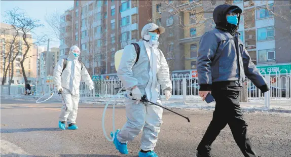  ??  ?? Un grupo de trabajador­es con trajes protectore­s y un habitante de la zona residencia­l de Beijing, China, después de la desinfecci­ón de la zona.