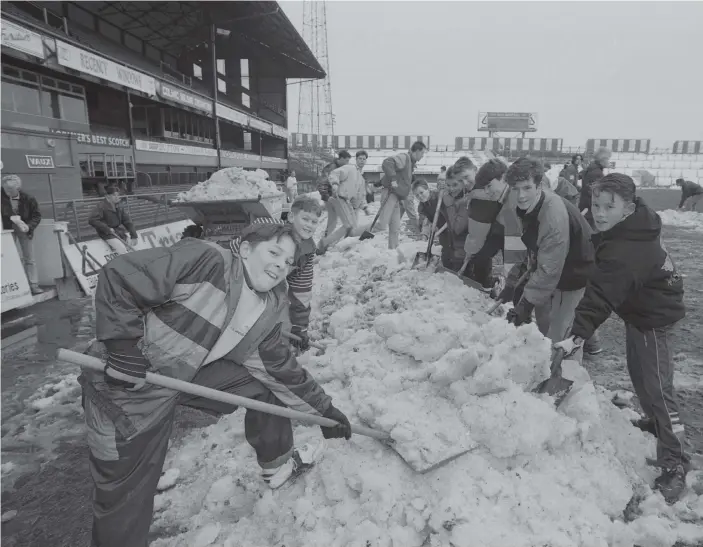  ??  ?? Taking advantage of the half-term holiday to earn a free visit to the next day’s match, these youngsters help clear the snow from the Roker Park pitch.