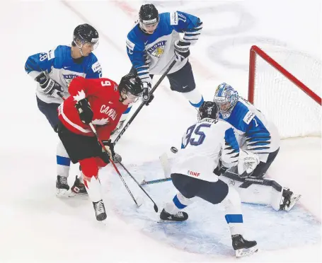  ?? GREG SOUTHAM ?? Connor Zary is surrounded by a trio of Finnish players as the puck heads toward Finland's goalie Kari Piiroinen during world juniors action Thursday in Edmonton. On the same day, the Flames first-round draft pick (24th overall) also signed an entry-level contract with Calgary.