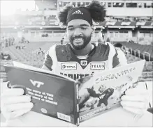  ?? COLE BURSTON THE CANADIAN PRESS ?? Montreal Alouettes defensive tackle Woody Baron poses with his children’s book, #JustaGobbl­er, on the sidelines.