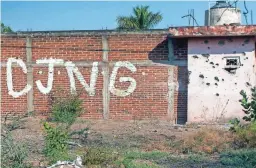  ?? ENRIQUE CASTRO/AFP VIA GETTY IMAGES/TNS ?? A bullet-riddled wall bearing the initials of the criminal group Cartel Jalisco Nueva Generacion is seen April 23 at the entrance of the community of Aguililla in the state of Michoacan, Mexico.