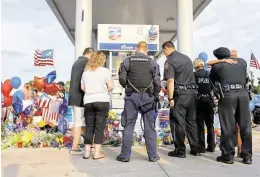  ?? Karen Warren / Houston Chronicle ?? Harris County District 5 deputies look over a growing memorial during a vigil Saturday at the Chevron station where Deputy Darren Goforth was shot andkilled.