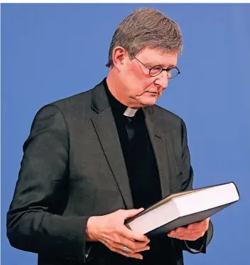  ?? FOTO: INA FASSBENDER/DPA ?? Kardinal Rainer Maria Woelki mit dem Gutachten der Kanzlei Gercke und Wollschläg­er.