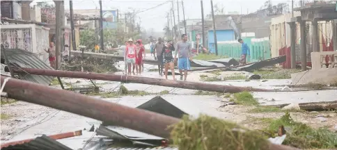  ??  ?? People walk on a damaged street after the passage of Hurricane Irma in Caibarien, Cuba. — Reuters photo