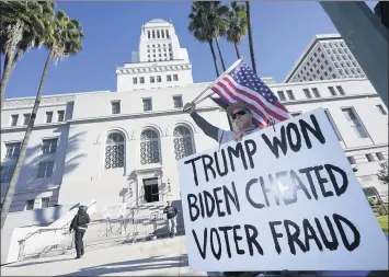  ?? MARCIO JOSE SANCHEZ — THE ASSOCIATED PRESS ?? A protester holds a sign outside Los Angeles City Hall on Jan. 6. One key to 2020 voting in the Inland Empire was whether voters lived in rural or urban areas. Joe Biden held sway in urban areas, Donald Trump in more rural ones.