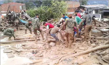  ?? Associated Press photo ?? In this handout photo released by the Colombian National Army, soldiers and residents work together in rescue efforts in Mocoa, Colombia, Saturday after an avalanche of water from an overflowin­g river swept through the city as people slept. The...