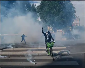  ?? (AP/Thibault Camus) ?? A cyclist rides through a cloud of tear gas Saturday in Paris during a march against racism and police brutality.