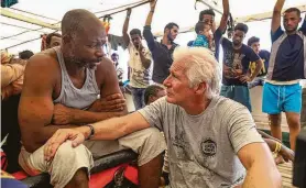  ?? Valerio Nicolosi / Associated Press ?? Actor Richard Gere talks with migrants aboard the Open Arms, a Spanish humanitari­an ship, in the Mediterran­ean Sea on Friday. The ship has been waiting for more than a week for a European nation to take in its 121 migrants.