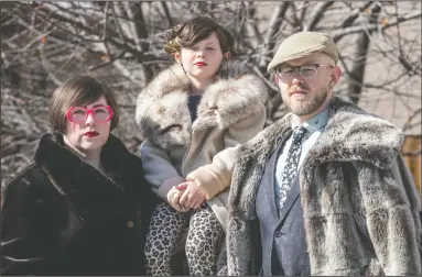  ?? CP-HO PHOTO / NEIL ZELLER, ?? A Calgary freelance photograph­er has been keeping busy shooting “porch portraits” of families around the city since the COVID19 pandemic sapped his usual source of income. Devon LeClair, left, and her husband Pete Meadows pose for a portrait with their child Huxley LeClair Meadows in Calgary in a Wednesday handout photo.