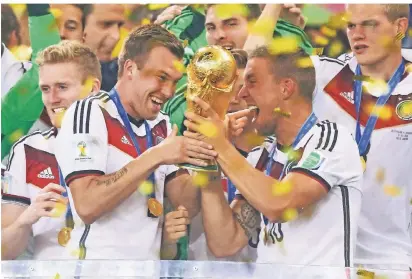  ?? FOTOS: IMAGO, JENNIFER SCHIMS ?? Der größte Moment in der Karriere: Kevin Großkreutz (l.) hält 2014 in Rio de Janeiro zusammen mit Lukas Podolski die Hand am WM-Pokal. Dahinter (v.l.): André Schürrle, Ron-Robert Zieler und Matthias Ginter.