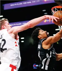  ?? (Reuters) ?? TORONTO RAPTORS center Jakob Poeltl (left) blocks the shot of Brooklyn Nets guard Spencer Dinwiddie on Tuesday night during second half of the Raptors’ 116-102 road triumph, Toronto’s ninth overall victory in a row.