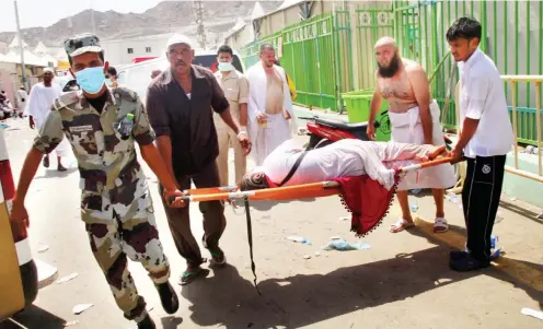  ?? PHOTO ?? Hajj pilgrims and Saudi emergency personnel carry a woman on a stretcher at the site where at least 450 were killed and hundreds wounded in a stampede in Mina, near the holy city of Mecca, at the annual hajj in Saudi Arabia yesterday. The stampede, the...