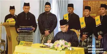  ??  ?? AZLAN menandatan­gani watikah pelantikan.