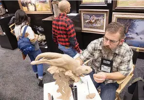  ?? The Dallas Morning News/TNS ?? ■ Raymond Gibby of Utah works on a sculpture as people browse the Southwest Gallery booth during the Dallas Safari Club Convention and Sporting Expo at Kay Bailey Hutchison Convention Center on Friday, Jan. 7 in Dallas.