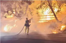  ?? RYAN CULLOM/VENTURA COUNTY FIRE DEPARTMENT ?? A firefighte­r works to put out a blaze early Tuesday in Santa Paula, Calif. Authoritie­s said the file broke out Monday and grew wildly in the hours that followed.