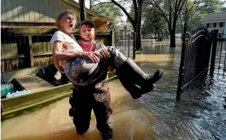  ?? REUTERS ?? North Houston resident Nancy McBride reacts as she returns to her home for the first time, carried by volunteer Cody Collinswor­th, since Harvey’s floodwater­s arrived.
