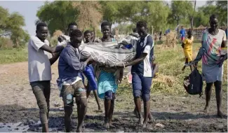  ?? ?? Children in Sudan carrying a corpse.