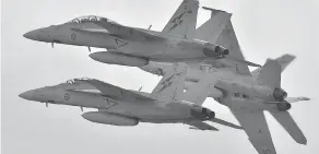  ?? PAUL CROCK / AFP / GETTY IMAGES ?? Royal Australian Air Force F-18 Hornets perform during an airshow near Melbourne in 2015. The Canadian government is looking at upgrading its fleet of CF-18s with these jets, the Australian equivalent, as a stopgap measure after it cancelled an order...