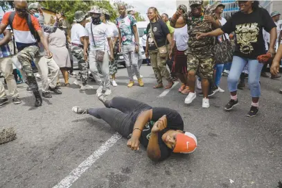  ?? Picture: AFP ?? ROLY-POLY. A supporter of Operation Dudula on the ground yesterday, while others sing and chant outside the Johannesbu­rg Central Police Station where their leader, ‘Lux’ Dlamini, is in custody.