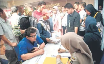  ??  ?? Family members of victims of the ill-fated Lion Air flight JT 610 submit papers and photograph­s of their lost relatives at a disaster victim identifica­tion unit at a police hospital in Jakarta.
