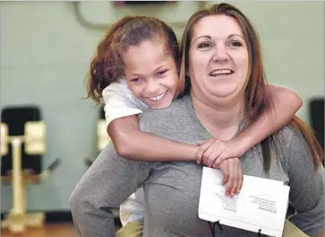  ?? Algerina Perna Baltimore Sun ?? CIARA WISEMAN, 8, gets a piggyback ride from her mother, Amanda Cooper, at the Maryland Correction­al Institutio­n for Women. The Girl Scouts Beyond Bars program allows girls to visit their incarcerat­ed moms.