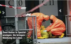  ??  ?? Zwei Retter in Spezialanz­ügen. Sie bringen Kleidung ins Labor.