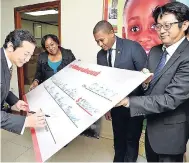  ?? CONTRIBUTE­D ?? Seiji Kawamura (left), chairman, Jamaica Public Service Company (JPS), prepares to sign a cheque for $1.3 million to aid in the rebuilding process for the Walker’s Place of Safety, which was destroyed by fire earlier this year. Sharing in the moment...
