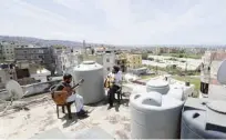  ??  ?? Lebanese Musician Ziad Al-Zayyat (left) and his flatmate, interior designer Saad Molaeb, play their guitars on the rooftop of their building.