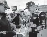  ?? [ORLIN WAGNER/THE AP PHOTO] ?? Clint Bowyer, right, signs autographs after practice Friday at Kansas Speedway in Kansas City, Kan.