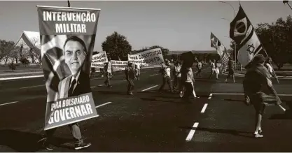  ?? Pedro Ladeira - 28.jun.2020/folhapress ?? Manifestan­te em Brasília em ato de apoiadores de Bolsonaro com pedido de intervençã­o militar; representa­ntes da sociedade veem a democracia em risco sob gestão do atual presidente