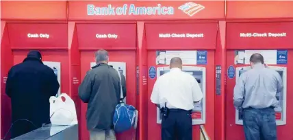  ?? — Reuters ?? Customers use ATMS at a Bank of America branch office.