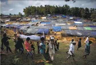  ?? K M Asad / AFP / Getty Images ?? Rohingya men carry the body of 68-year-old man during his funeral at a refugee camp in Bangladesh. His relatives say he was shot by Myanmar’s army while crossing a river.