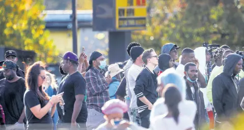  ?? AP PHOTOS ?? Dozens of onlookers gathered at the scene where rapper Young Dolph was killed at a cookie shop.