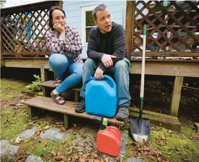  ?? ROBERT F. BUKATY/AP ?? Lucinda Tyler and Aaron Raymo use plastic containers to fill a heating oil tank at their home in Jay, Maine.