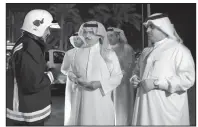  ?? AP/Bahrain News Agency ?? Sheikh Rashid bin Abdullah Al Khalifa (center), Bahrain’s interior minister, talks with an emergency services worker Saturday at the scene of an oil-pipeline explosion.