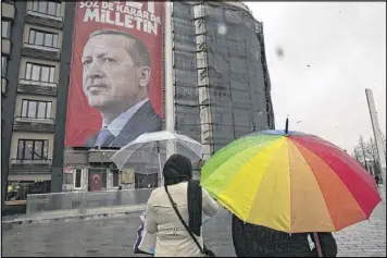  ?? LEFTERIS PITARAKIS / ASSOCIATED PRESS ?? People walk in Istanbul’s Taksim Square on Tuesday near a poster of Turkish President Recep Tayyip Erdogan. Erdogan is angry after the Netherland­s prevented two Turkish ministers from holding campaign rallies over the weekend.