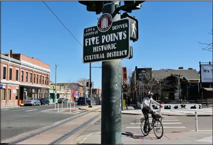  ?? HYOUNG CHANG — THE DENVER POST ?? A cyclist rides by a Five Points neighborho­od sign March 19.