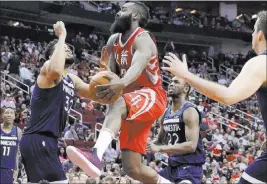  ?? Michael Wyke ?? The Associated Press Rockets guard James Harden leaps toward the basket between Timberwolv­es forward Andrew Wiggins (22) and center Karl-anthony Towns in the second half of Houston’s 120-102 win Friday at Toyota Center.