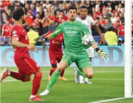  ?? ?? Real Madrid players and staff celebrate the Champions League triumph (right); Real goalkeeper Thibaut Courtois stops a shot from Liverpool forward Mohamed Salah (above); Vinicius Jr exults after scoring the winning goal (below)