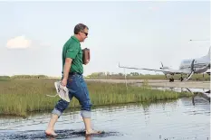  ?? DON HEALY FILES ?? Premier Brad Wall removed his socks and shoes to step across the flooded runway at the Melville airport to board a flight back to Regina after an aerial tour of the flood-ravaged southeast in 2014.