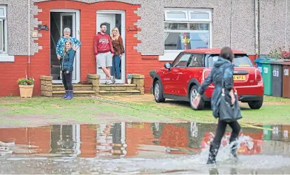  ?? Picture: Kris Miller. ?? Residents had to be evacuated from houses in the Park Road area of Rosyth. The Geaton and Paterson families keep an eye on the rising water near their homes.