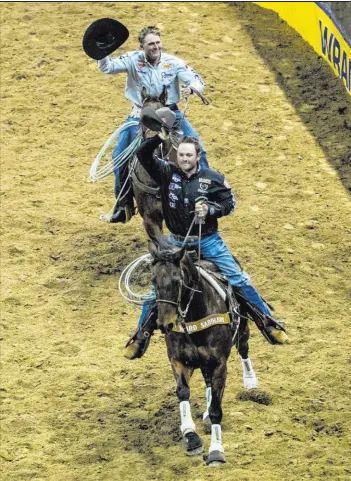  ?? L.E. Baskow Las Vegas Review-journal @Left_eye_images ?? Tyler Wade, of Terrell, Texas, and Trey Yates of Pueblo, Colo., celebrate their team roping win during the opening night Thursday of the National Finals Rodeo at Thomas & Mack Center.