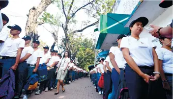  ?? SUNSTAR FOTO / AMPER CAMPAÑA ?? WOMEN COMPOSE 76% OF THIS BATCH. A student walks past neat lines of recruits waiting outside the Police Regional Office 7 headquarte­rs in Cebu City.