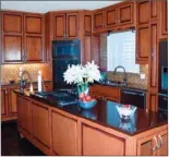  ??  ?? Sparkling glass tile backsplash­es complement the kitchen’s wood cabinetry and stone counters.