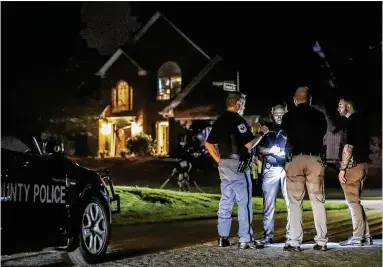  ?? JOHN SPINK/AJC ?? Law enforcemen­t officers gather outside a home in a neighborho­od in west Cobb early Friday morning after two sheriff’s deputies were killed in an apparent ambush while attempting to serve a warrant at the home. The deputies had returned to their vehicle after knocking on the door when a car pulled up Thursday night and they were shot to death.