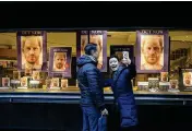  ?? KIRSTY WIGGLESWOR­TH / AP ?? A woman takes a photo in front of a shop in London on Tuesday. In his new book, Prince Harry lambastes the U.K. press and the royal family.