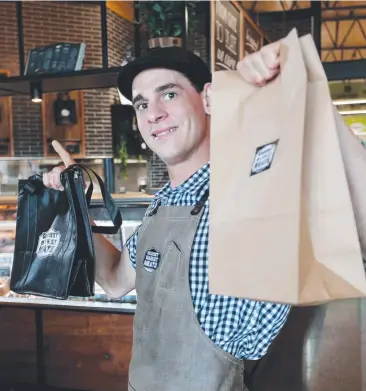  ??  ?? OLD SCHOOL: Head Butcher Breon Nolan with the re-usable cooler and paper bags that Gourmet Market Meats at Bar St Markets has available. Picture: STEWART McLEAN